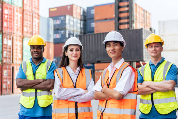 Portrait group of male and female worker working in container terminal. Attractive business man and woman laborer stand with confidence after process orders at warehouse logistic in cargo freight ship stock photo