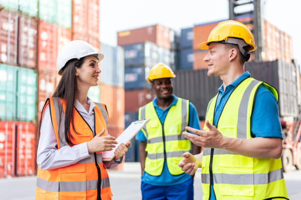 Caucasian business man and woman worker working in container terminal. Attractive engineer people processes orders and product at warehouse logistic in cargo freight ship for import export in harbor. stock photo