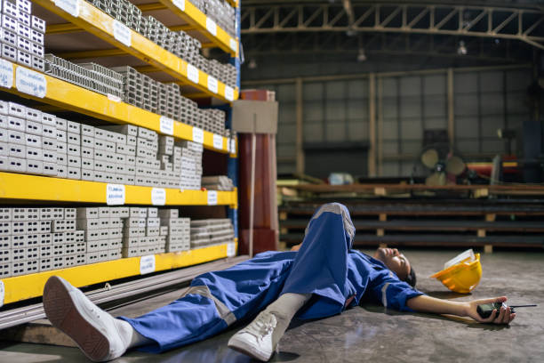 istock Asian industrial worker falling on the ground while work in warehouse. Attractive young handsome man industry factory engineer wearing safety yellow helmet having accident alone at manufactory plant. 1420013966