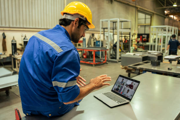 kaukasische gutaussehende männliche industriearbeiter arbeiten in produktionsanlagen. attraktiver junger mann industrie fabrik ingenieur verwenden laptop-computer videoanruf mit team, um produktherstellungsanlage zu verarbeiten. - building contractor computer internet construction worker stock-fotos und bilder