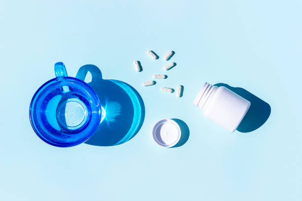 Pills and glass of water on blue background. Medicine, healthcare concept stock photo