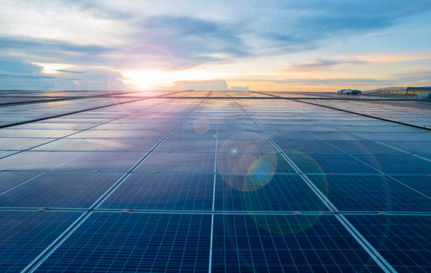 Sunset rays over a photovoltaic power plant, solar panels on a roof stock photo