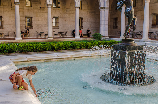 Courtyard of the Boston Public Library during summer day.\nA teenage girl is touching the water of the fountain.\n\nThis was not staged at all. This girl was just there enjoying the courtyard and I took pictures of her when she decided to play with the water.