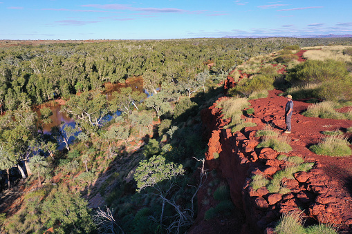 Aerial landscape view of Australian man  standing on a cliff looking at Fortescue River in Millstream Chichester National Park in the Pilbara region Western Australia