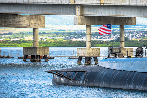 Pearl Harbor, USA - April 1st, 2022: USS Bowfin and American Flag. National historic sites at Pearl Harbor tell the story of the battle that plunged US into World War II.
