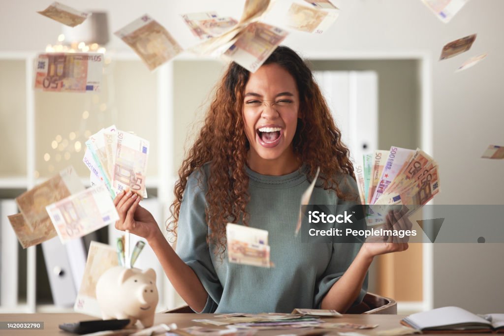 One happy young mixed race woman feeling rich and successful while throwing money at home. Excited hispanic celebrating after saving and budgeting finances. Planning for the future or win a lottery Currency Stock Photo
