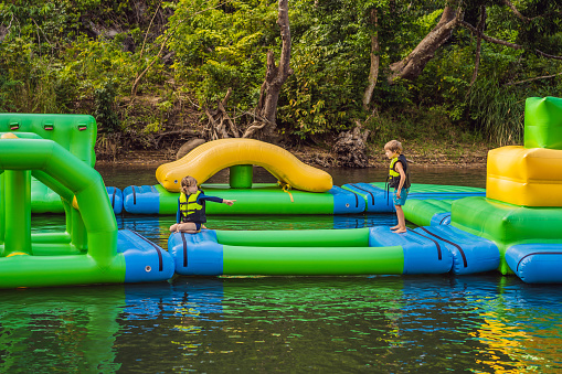 Two boy runs an inflatable obstacle course In the lake.