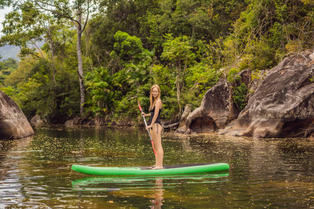 istock SUP Stand up paddle board woman paddle boarding on lake standing happy on paddleboard on blue water. Action Shot of Young Woman on Paddle Board 1420033549