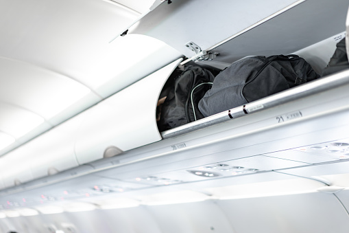 luggage on the top airplane shelf overhead passenger seat