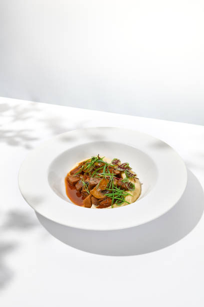 istock Elegant stew beef with mashed potatoes in  restaurant. Beef bourguignon on light background with shadows of leaves Braised black angus meat with potato cream in summer menu 1420036068