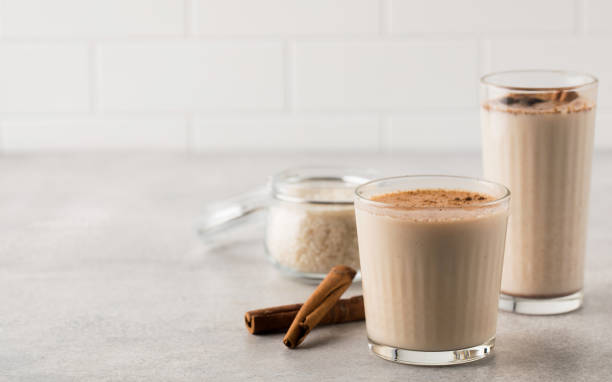 Glasses with a cold drink based on Horchata rice, cinnamon sticks and a jar of rice on a light background. Copy space Glasses with a cold drink based on Horchata rice, cinnamon sticks and a jar of rice on a light background. Vegetarian soft drink, national cuisine. Copy space sedge stock pictures, royalty-free photos & images