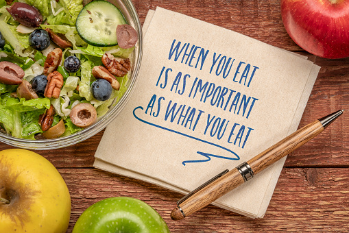 When you eat is as important as what you eat - inspirational note on a napkin with a healthy salad and apples, healthy eating and lifestyle concept