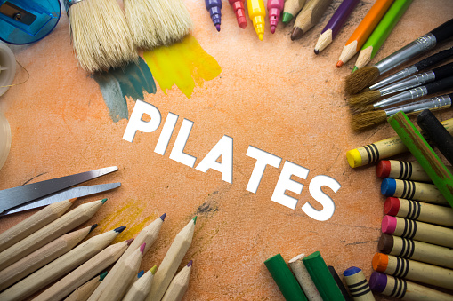 Overhead shot of school supplies with Pilates text. Brushes, pencils, artistic tools. Art And Craft Work Tools.