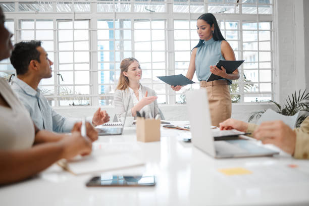 istock Female intern, assistant or employee handing out an information document to a team during a boardroom meeting. Group of business people discussing the mission, vision and strategy for company growth 1420050715
