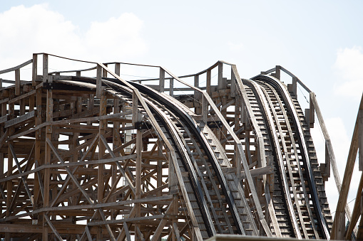 Wooden roller coaster track with blue sky in the background.