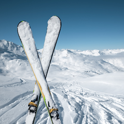 Pair of crossed skis on top of ski slope with view on the mountains. Val Thorens, France.