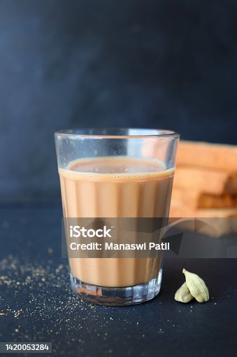 istock Tea Time Snack - Healthy Wheat rusk served with Indian hot masala tea, over black background with whole cardamom. also known as Mumbai cutting chai. with Copy space 1420053284