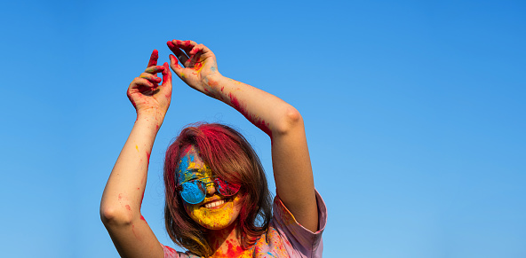 Woman covered in holi powder against blue sky. Holi colours festival.