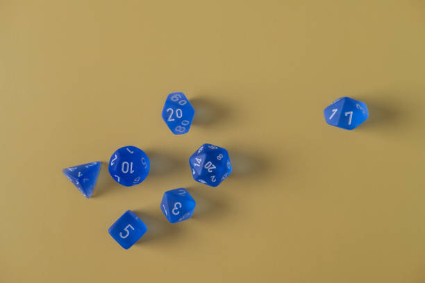 黄色の背景にランダムに散らばった多面的な青いサイコロ - dice chance number chaos ストックフォトと画像