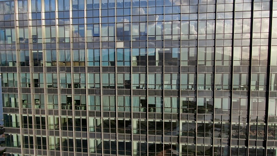 View of a modern glass skyscraper reflecting the blue sky,blue toned image.