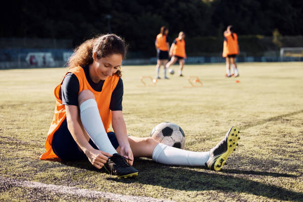 istock Female player tying shoelace during soccer training on a stadium. 1420056764