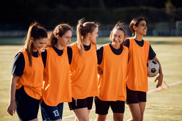 istock Women's soccer team walking embraced on playing field. 1420056787