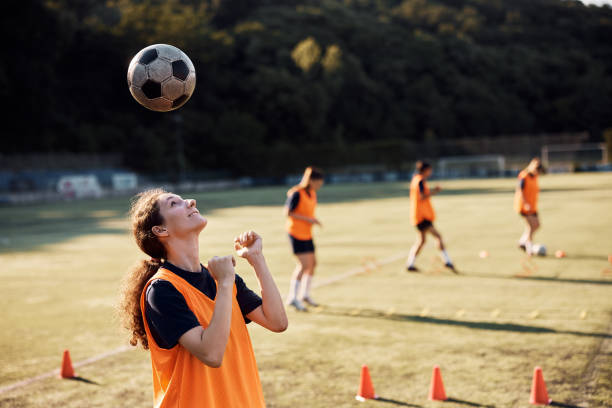 istock Smiling female soccer player heading the ball during practice on playing field. 1420056864