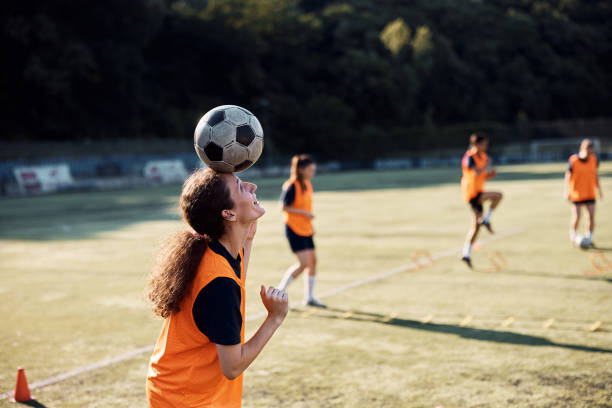 istock Happy player balancing soccer ball on her head during sports training. 1420056866