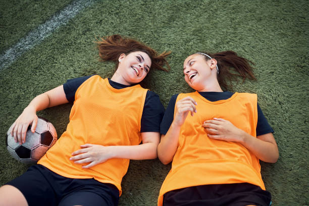 istock Happy female soccer players having fun while lying down on grass. 1420058009