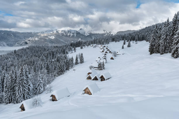 old cottages in a snowfield on a hillside with shadows at sunrise at Passo Gardena in winter