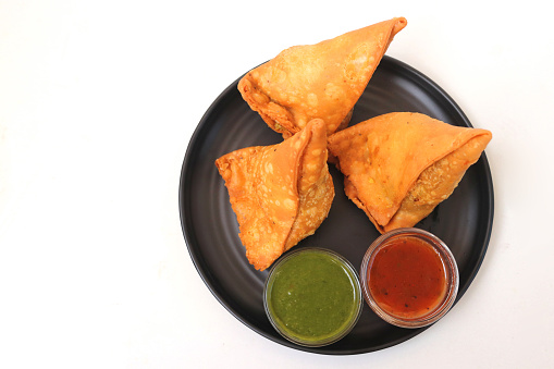 Vegetarian Aloo samosa or samosas. Indian special traditional street food. Famous Indian Punjabi samosa filled with spicy boiled potato mixture. served with green and red chutneys. Copy space.