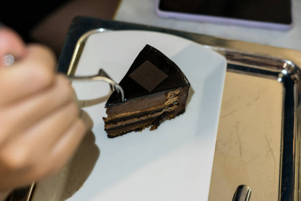 istock chocolate cake is on the white plate hand with fork 1420063247