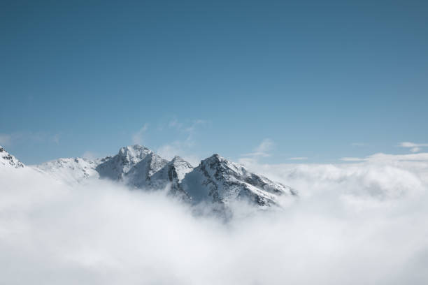 Snowcapped mountain peaks looking out through the fog.