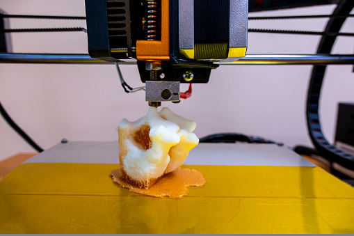 printing vertebrae on a 3d printer. artificial body parts printed on a 3d printer. New era of medicine. printing on a 3d printer. orange trident is printed with plastic on a 3d printer