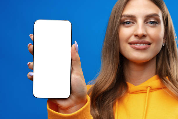 istock Young woman showing big blank cellphone screen on blue background in studio 1420065413