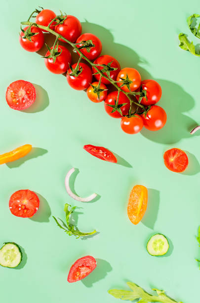 istock Fresh tomatoes and cucumbers on a green background with hard shadows. 1420067720