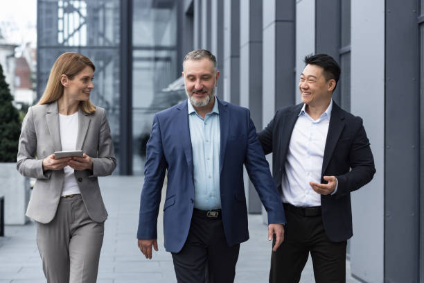 istock A diverse team of IT specialists, senior and experienced engineers managers team leaders, a group of three workers happily strolling outside an office building, colleagues in business suits 1420067925