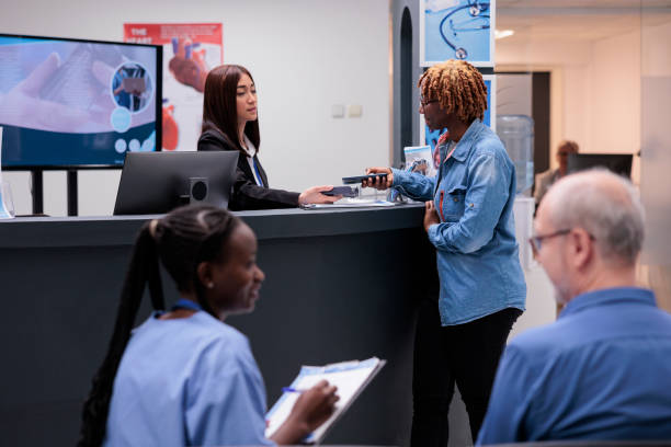 afroamerikanerin bezahlten termin - healthcare and medicine receptionist paying credit card stock-fotos und bilder