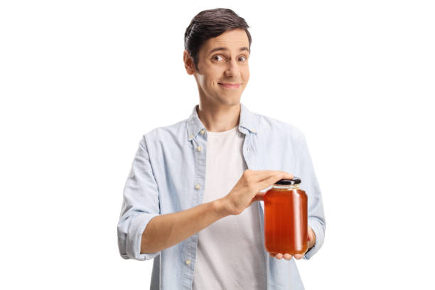 istock Young man holding a jar of honey and smiling 1420069973