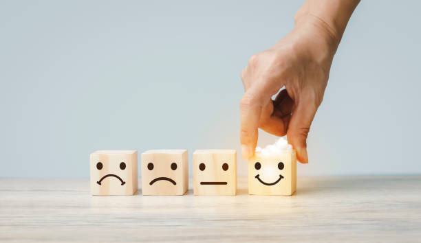 istock Customer services best excellent business rating experience. Satisfaction survey concept. Hand of a businessman chooses a smiley face on wood block cube 1420072239