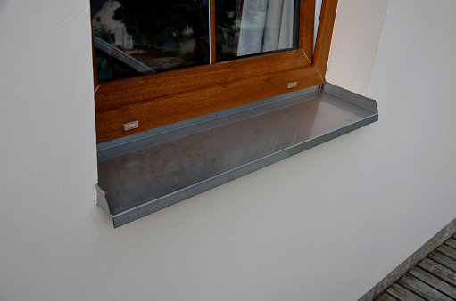Stainless steel plate under the window. durable gutter protects the facade from water runoff. plastic window frame with imitation oak wood, runoff