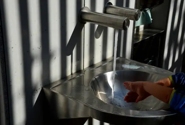 Photo of stainless steel sink with automatic battery reminds the interior of an airplane. however, it is on the bike path by the public toilets. There is also a changing table for babies, folded out