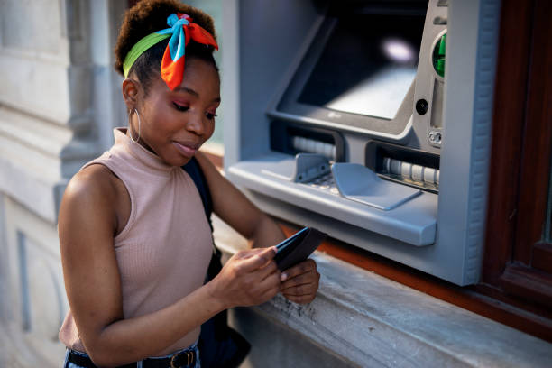 Attractive young woman withdrawing money from credit card at ATM. stock photo