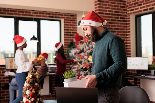 Unhappy man getting fired on christmas eve, feeling depressed and upset after being discharged from business job. Losing work and being jobless on xmas day, career failure in festive workplace.