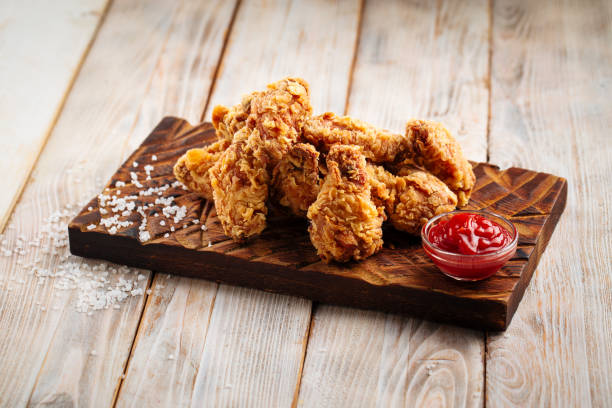 istock Fried chicken wings with ketchup on wooden board 1420079463