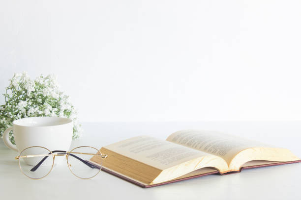 istock Book with white flowers, coffee cups and glasses over the white wall. 1420084676