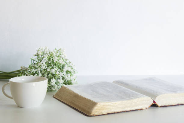 istock Open book with white flowers and coffee cup over the white table. 1420084677