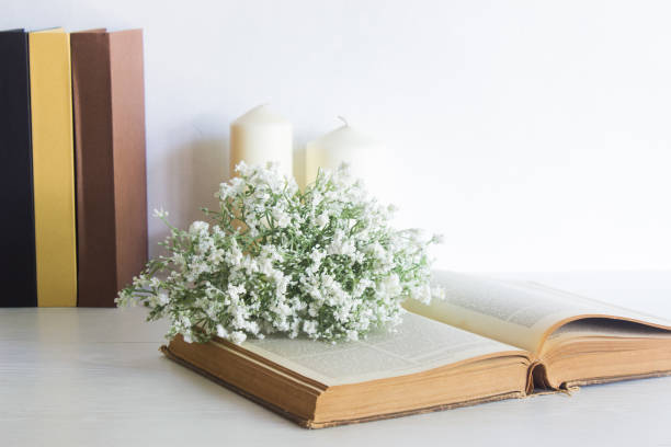 istock Books with white flowers and white candles over the white wall. 1420084700