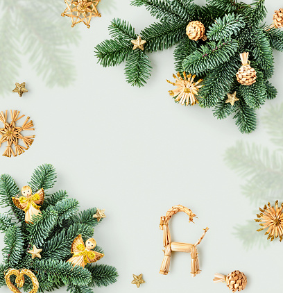 Fir tree branch with christmas decoration frame and creative card. Golden angel, heart, snowflake and stars composition on bright background. Design element. Flat lay, top view