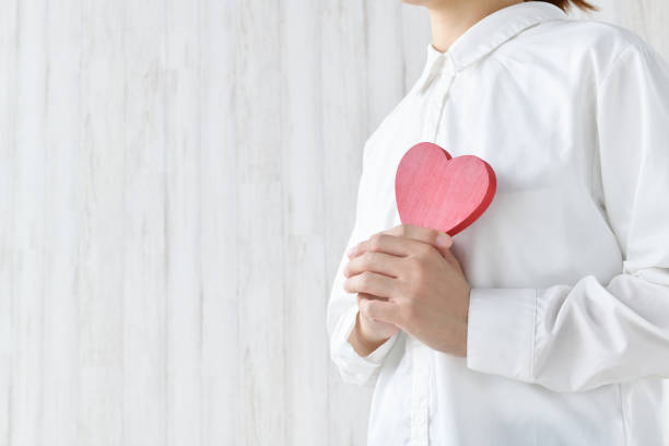 乳房に心臓の物体を抱く女性 - 悩み ストックフォトと画像